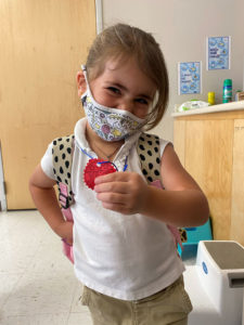A young girl holds up a "Vote" medallion